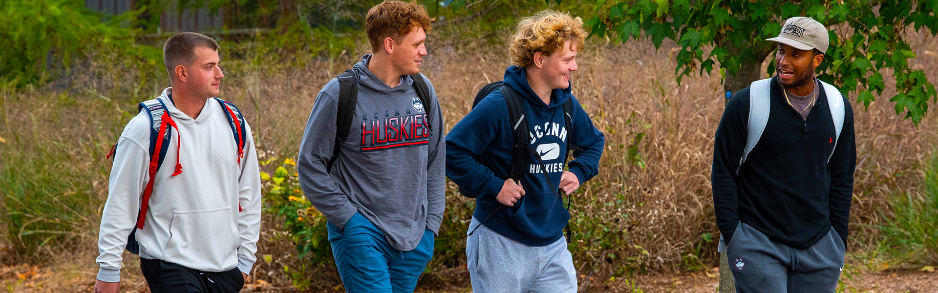 four uconn students walking and wearing uconn sweatshirts